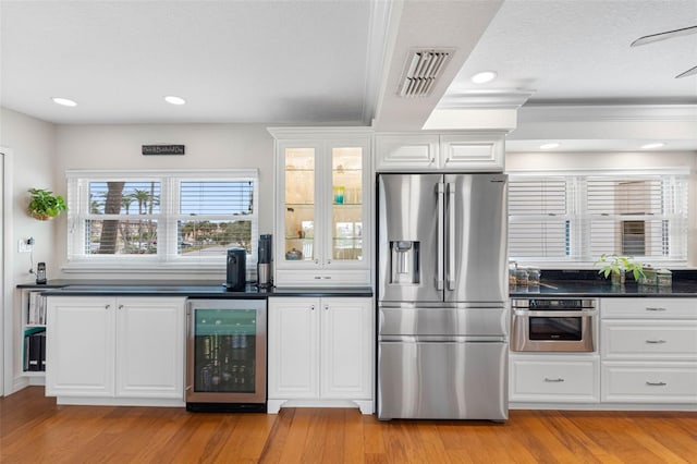 12360 Capri Cir N Unit 106, Treasure Island, FL 33706 - kitchen with appliances with stainless steel finishes, wine cooler, dark countertops, light wood-type flooring, and recessed lighting
