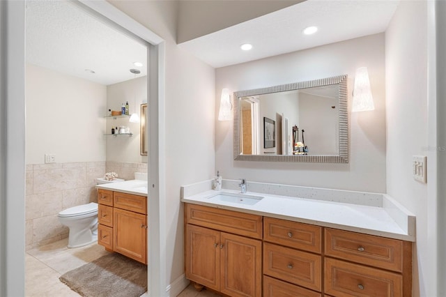 12360 Capri Cir N Unit 106, Treasure Island, FL 33706 - bathroom with toilet, vanity, tile patterned flooring, tile walls, and wainscoting