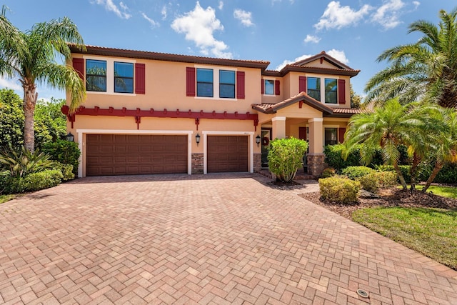 4611 Grand Preserve Pl, Palm Harbor, FL 34684 - mediterranean / spanish-style house featuring decorative driveway, a garage, a tiled roof, stucco siding, and stone siding