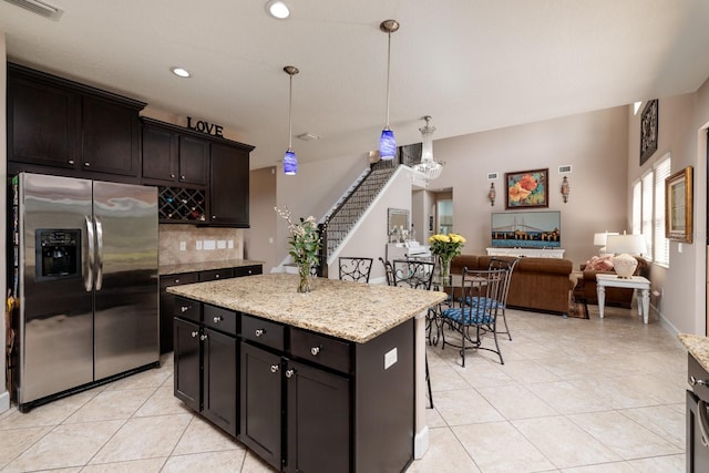 4611 Grand Preserve Pl, Palm Harbor, FL 34684 - kitchen featuring stainless steel refrigerator with ice dispenser, light tile patterned floors, decorative backsplash, hanging light fixtures, and a kitchen island