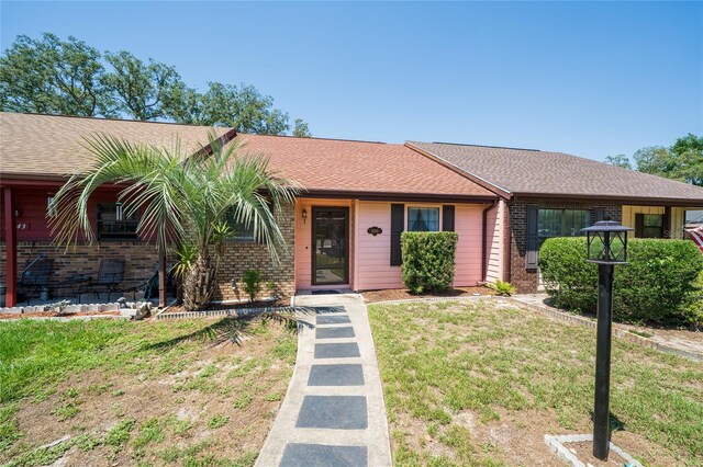 35145 Whispering Oaks Blvd, Dade City, FL 33523 - view of front of property featuring brick siding, a front lawn, and a shingled roof