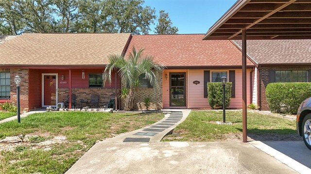 35145 Whispering Oaks Blvd, Dade City, FL 33523 - view of front of house with brick siding, a front lawn, and roof with shingles