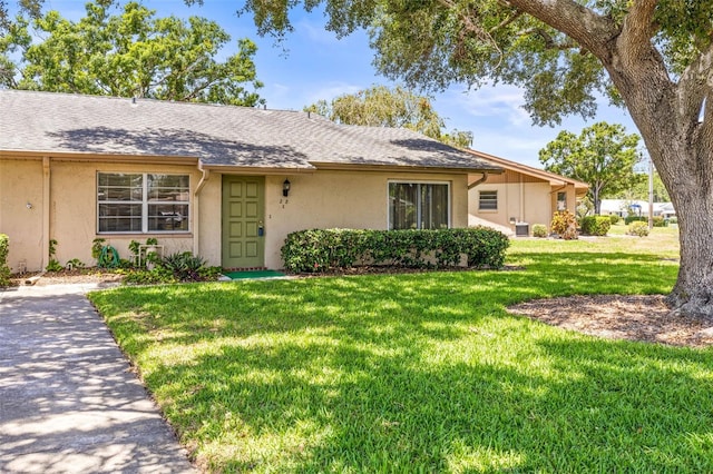 ranch-style home featuring stucco siding, a front lawn, and roof with shingles