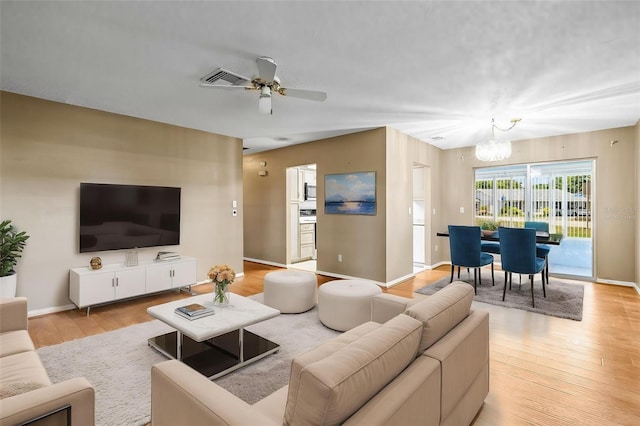 living area featuring a chandelier, wood finished floors, a ceiling fan, and baseboards