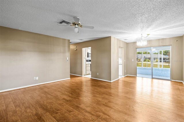 spare room featuring a chandelier, wood finished floors, a textured ceiling, and a ceiling fan