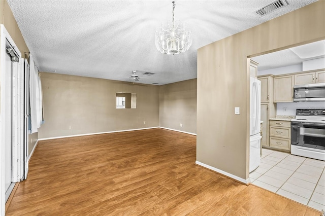 kitchen with range with electric stovetop, stainless steel microwave, a textured ceiling, light wood-style flooring, and open floor plan