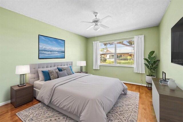 bedroom featuring light wood finished floors, baseboards, and a ceiling fan
