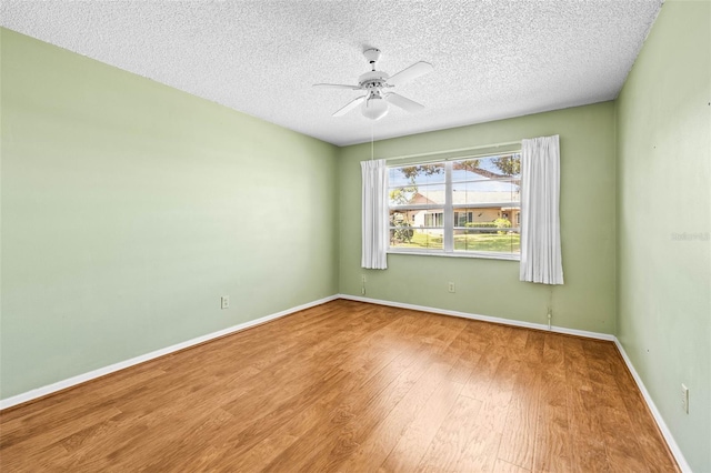 spare room featuring wood finished floors, ceiling fan, a textured ceiling, and baseboards