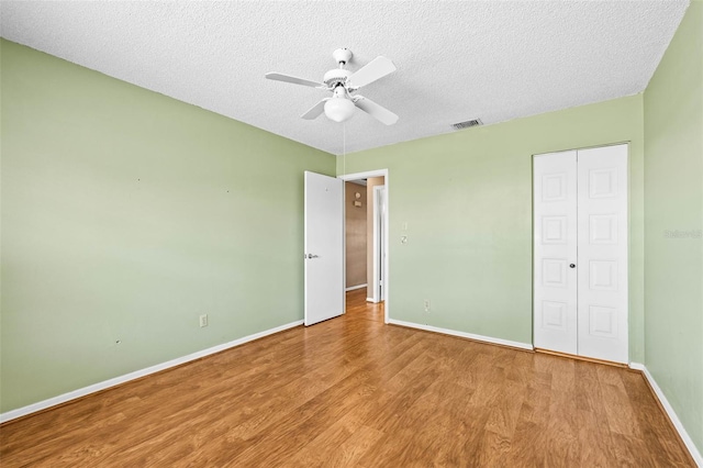 unfurnished bedroom featuring wood finished floors, baseboards, a textured ceiling, a closet, and a ceiling fan