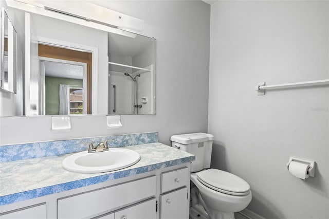bathroom featuring toilet, a shower, and vanity
