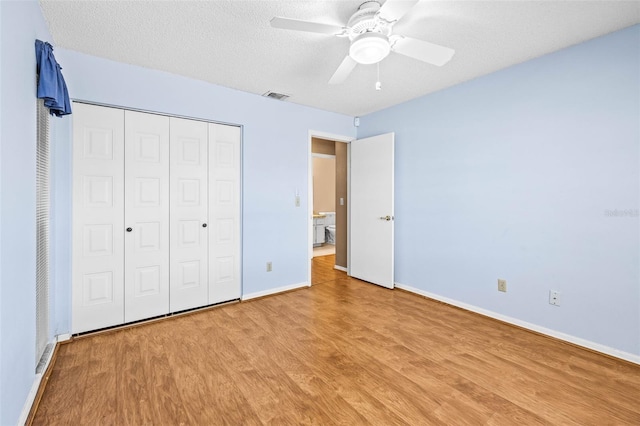 unfurnished bedroom featuring light wood finished floors, baseboards, a closet, a ceiling fan, and a textured ceiling