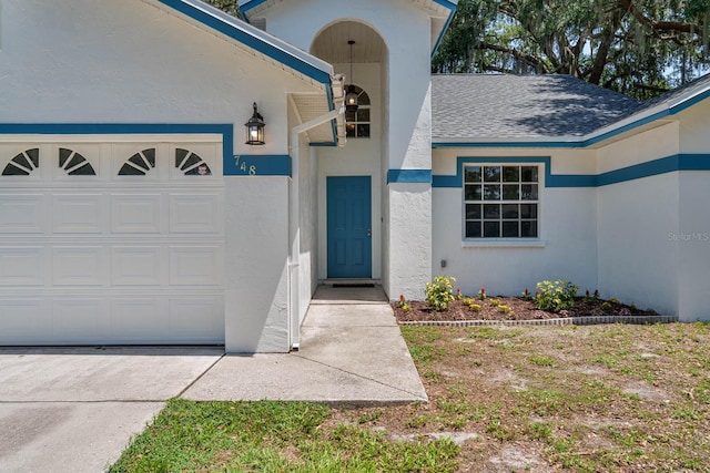 748 Sagewood Dr, Lakeland, FL 33813 - doorway to property featuring roof with shingles, stucco siding, an attached garage, and driveway