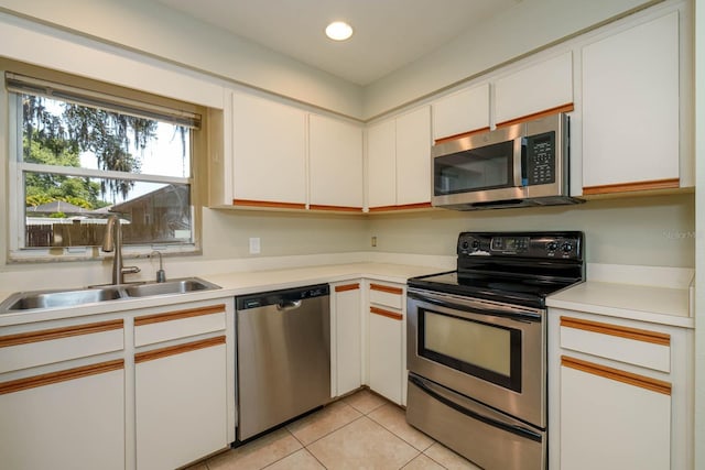 748 Sagewood Dr, Lakeland, FL 33813 - kitchen with stainless steel appliances, a sink, light countertops, white cabinetry, and light tile patterned floors