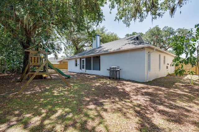 748 Sagewood Dr, Lakeland, FL 33813 - rear view of house with a playground, fence, concrete block siding, a chimney, and roof with shingles