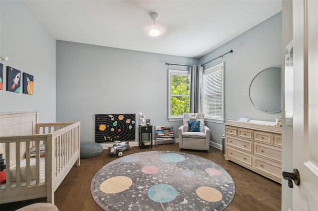807 W Kentucky Ave, Tampa, FL 33603 - bedroom featuring dark wood finished floors and a nursery area