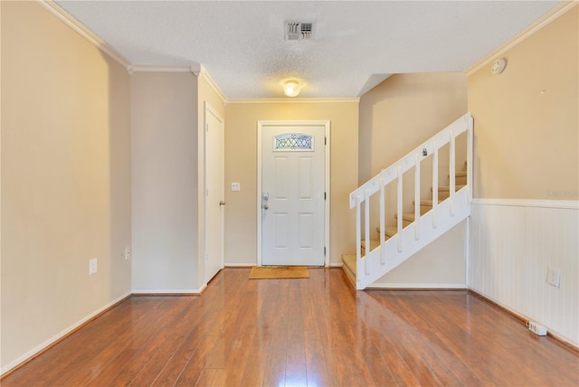 728 Waterbridge Dr, Winter Haven, FL 33880 - foyer entrance featuring ornamental molding, wood-type flooring, stairway, a textured ceiling, and a wainscoted wall