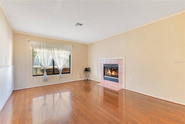 728 Waterbridge Dr, Winter Haven, FL 33880 - unfurnished living room with ornamental molding, wood finished floors, a tile fireplace, baseboards, and a textured ceiling