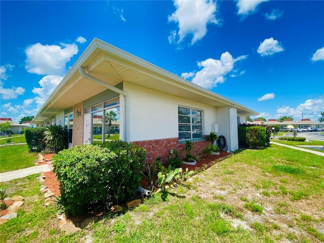 4351 Tahitian Gardens Cir Unit H, Holiday, FL 34691 - view of home's exterior with a yard, stone siding, and stucco siding
