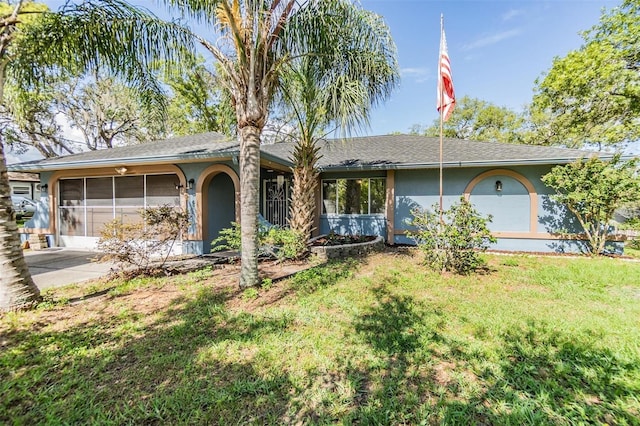 2308 Rio Cir, Spring Hill, FL 34608 - ranch-style house with stucco siding, a front yard, a shingled roof, and a sunroom