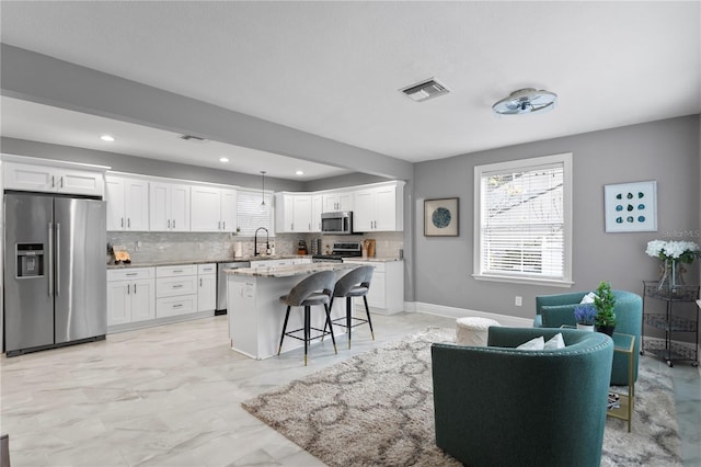kitchen featuring stainless steel appliances, a kitchen breakfast bar, tasteful backsplash, healthy amount of natural light, and recessed lighting