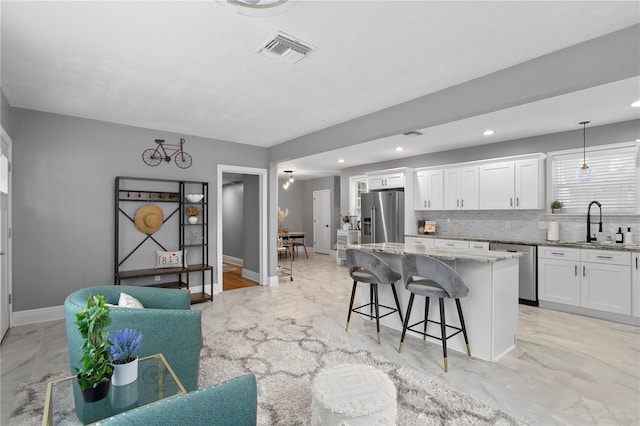 kitchen featuring appliances with stainless steel finishes, a kitchen bar, a sink, light marble finish floors, and recessed lighting