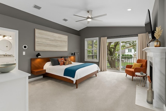 bedroom with lofted ceiling, access to exterior, a sink, light colored carpet, and a fireplace with flush hearth