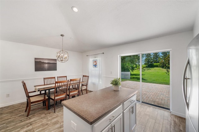 7103 Bridgeview Dr, Wesley Chapel, FL 33545 - kitchen with freestanding refrigerator, light wood finished floors, a chandelier, a kitchen island, and decorative light fixtures