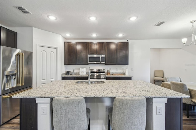 14282 Coronado Dr, Spring Hill, FL 34609 - kitchen with appliances with stainless steel finishes, dark wood-style floors, a kitchen bar, a textured ceiling, and a center island with sink
