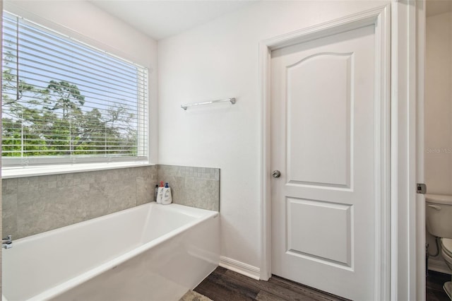 14282 Coronado Dr, Spring Hill, FL 34609 - bathroom with toilet, a bath, wood finished floors, and baseboards
