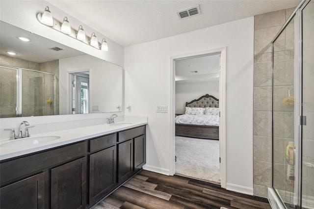 14282 Coronado Dr, Spring Hill, FL 34609 - ensuite bathroom with wood finished floors, a shower stall, double vanity, baseboards, and a textured ceiling