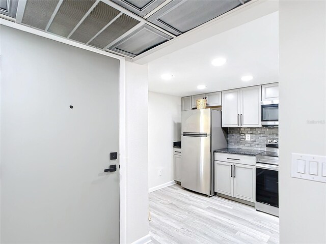 14130 Rosemary Ln Unit 3215, Largo, FL 33774 - kitchen with appliances with stainless steel finishes, light wood-type flooring, tasteful backsplash, baseboards, and dark countertops
