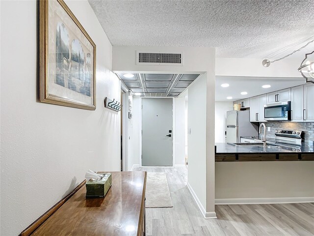 14130 Rosemary Ln Unit 3215, Largo, FL 33774 - corridor featuring light wood finished floors, a textured ceiling, baseboards, and a sink