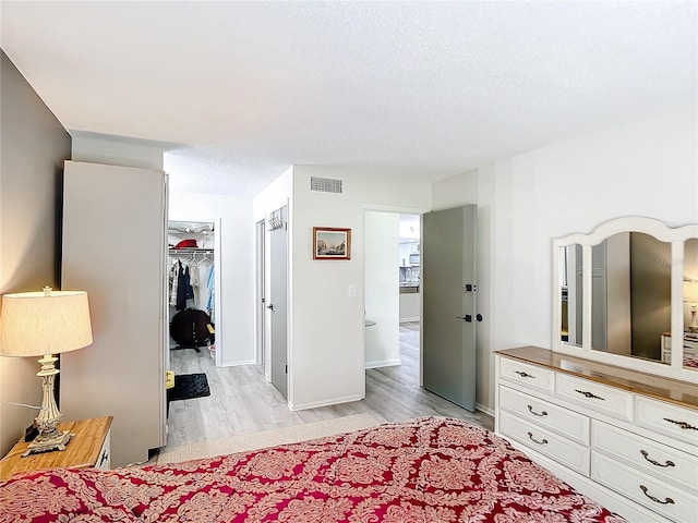 14130 Rosemary Ln Unit 3215, Largo, FL 33774 - bedroom featuring light wood-style floors, a spacious closet, a textured ceiling, a closet, and baseboards