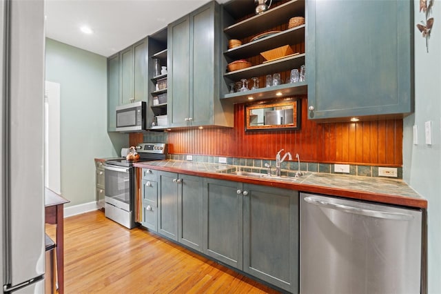 1001 E Crawford St, Tampa, FL 33604 - kitchen with stainless steel appliances, open shelves, a sink, decorative backsplash, and light wood-type flooring