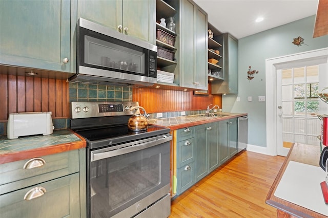 1001 E Crawford St, Tampa, FL 33604 - kitchen with stainless steel appliances, open shelves, tile countertops, decorative backsplash, and light wood finished floors
