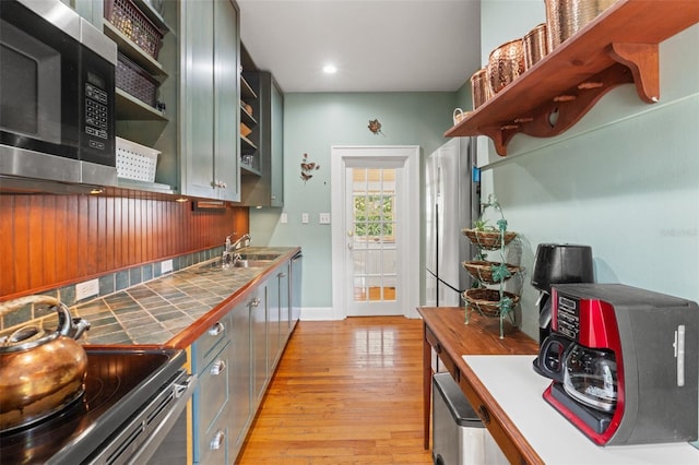 1001 E Crawford St, Tampa, FL 33604 - kitchen with open shelves, appliances with stainless steel finishes, a sink, light wood-type flooring, and tile counters