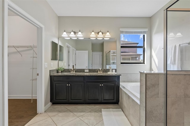 4690 Coachford Dr, Wesley Chapel, FL 33543 - bathroom featuring a spacious closet, a stall shower, a garden tub, double vanity, and tile patterned floors