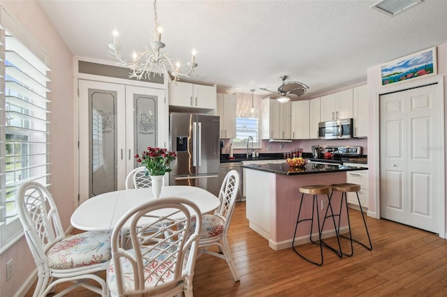 3227 Rose Arbor Dr, Hernando Beach, FL 34607 - kitchen with appliances with stainless steel finishes, a chandelier, dark countertops, a kitchen island, and white cabinetry