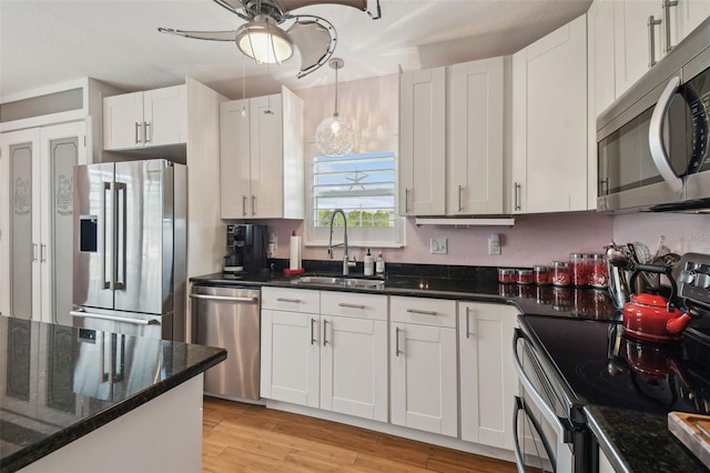 3227 Rose Arbor Dr, Hernando Beach, FL 34607 - kitchen with appliances with stainless steel finishes, a sink, white cabinetry, light wood-style flooring, and a ceiling fan