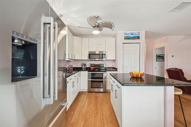 3227 Rose Arbor Dr, Hernando Beach, FL 34607 - kitchen featuring appliances with stainless steel finishes, a breakfast bar, light wood-type flooring, and white cabinetry
