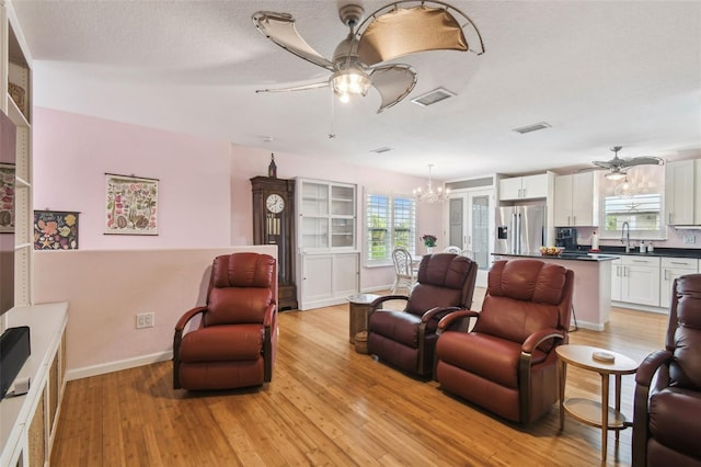 3227 Rose Arbor Dr, Hernando Beach, FL 34607 - living room with a ceiling fan, light wood finished floors, baseboards, and a chandelier