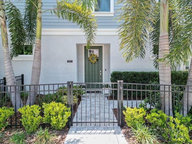property entrance featuring fence, stucco siding, and a gate