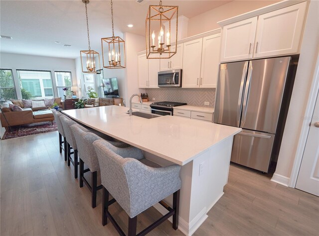 kitchen featuring stainless steel appliances, a sink, a chandelier, open floor plan, and recessed lighting