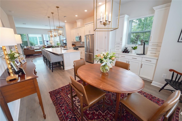 dining space with a chandelier, plenty of natural light, wood finished floors, and recessed lighting