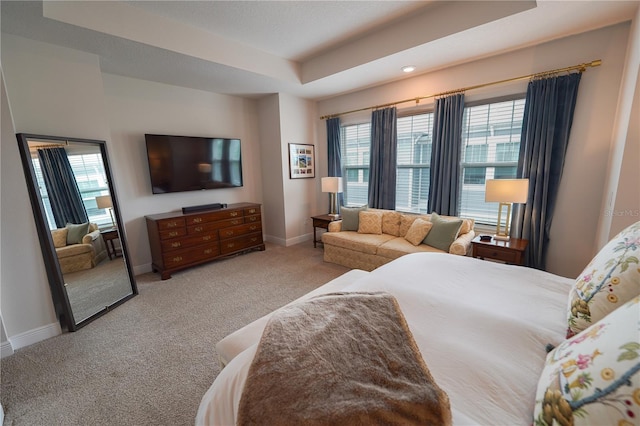 bedroom featuring carpet floors, a raised ceiling, and baseboards