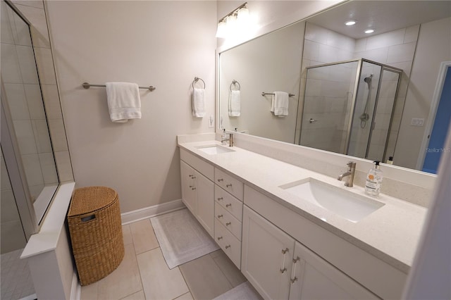 full bath with a stall shower, double vanity, tile patterned floors, and baseboards