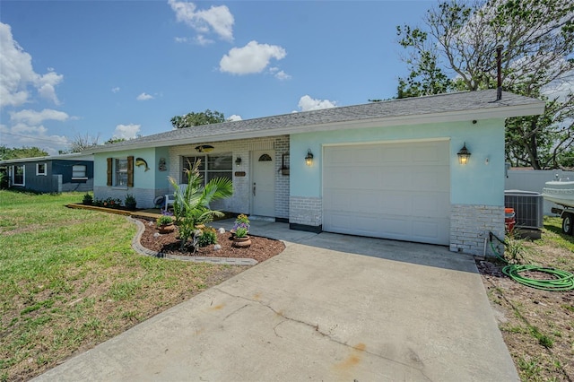 ranch-style house with a garage, driveway, a front yard, brick siding, and central air condition unit