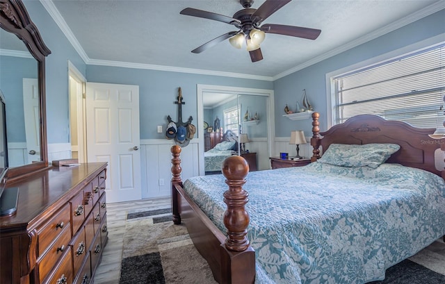 bedroom featuring multiple windows, light wood finished floors, a closet, a wainscoted wall, and ornamental molding