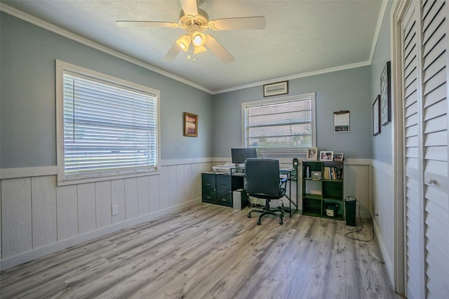 home office with healthy amount of natural light, wood finished floors, a wainscoted wall, crown molding, and a ceiling fan