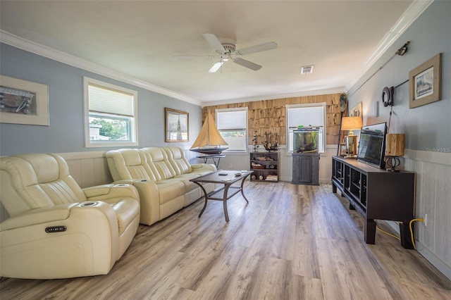 living area with healthy amount of natural light, wood finished floors, ornamental molding, ceiling fan, and wood walls